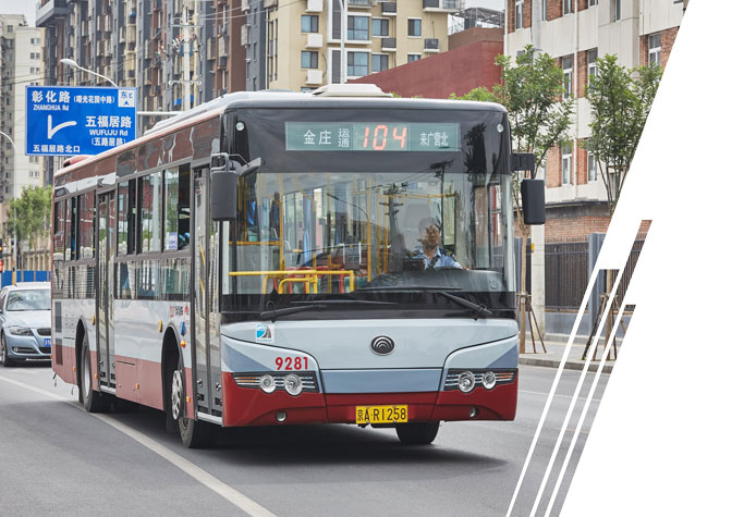 A red, white and blue bus travels under an overpass.